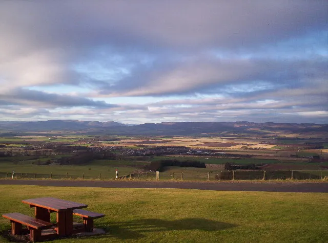 A view of the pastoral Mearns in Aberdeenshire. A picnic table in the foreground and in the background is the Eastern Cairngorms. It's an overcast day, which creates pretty lighting in the p